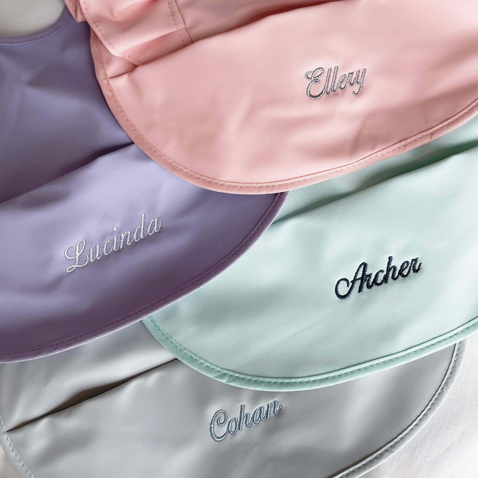 RAPH&REMY® Premium Bib in a pastel color palette, waterproof and durable. Pink, Purple, Grey, and Green