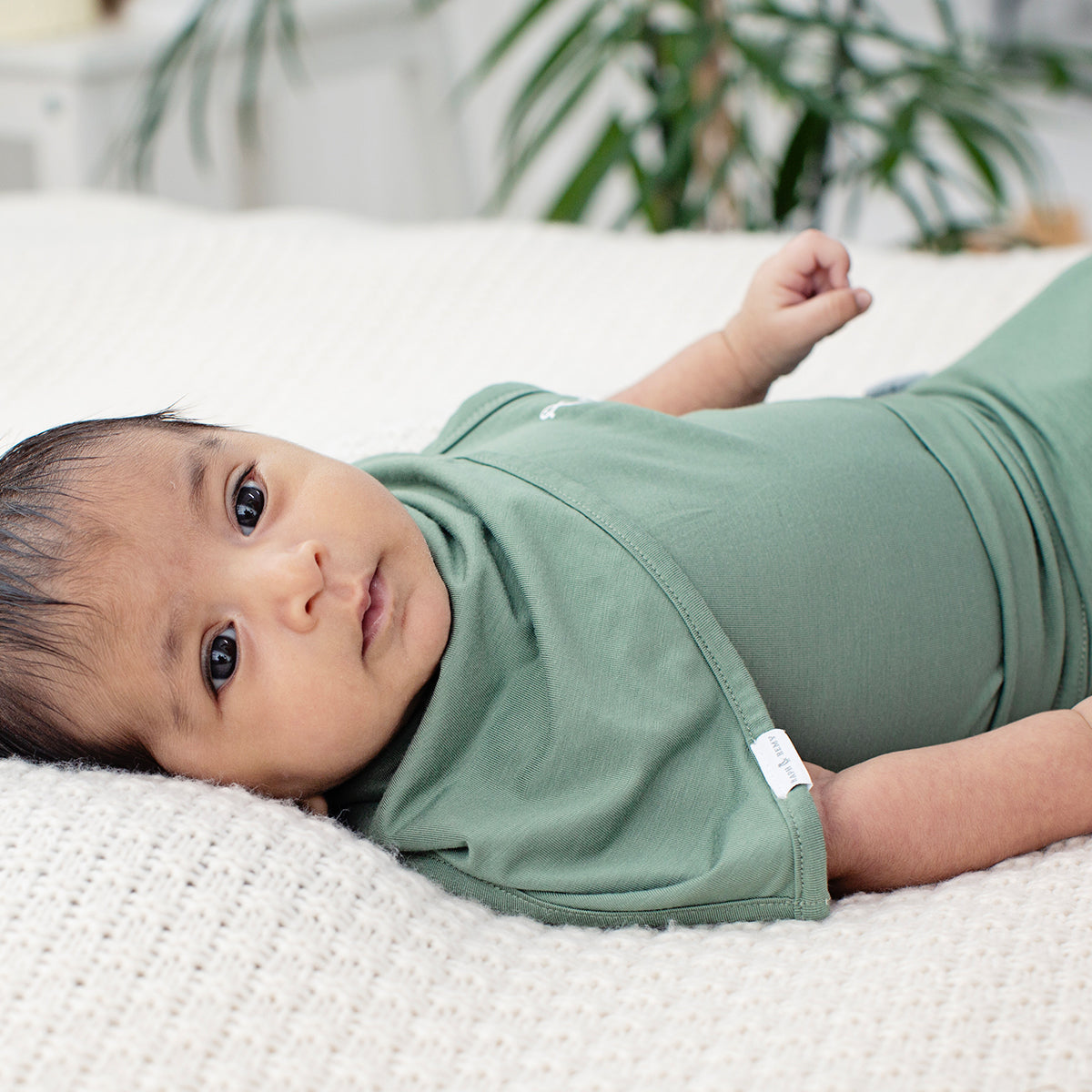 Baby with sensitive skin wearing organic bamboo bib by RAPH&REMY® in army green