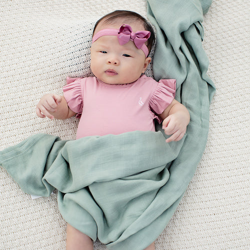 Baby girl wrapped in RAPH&REMY® bamboo swaddle in green pastel color