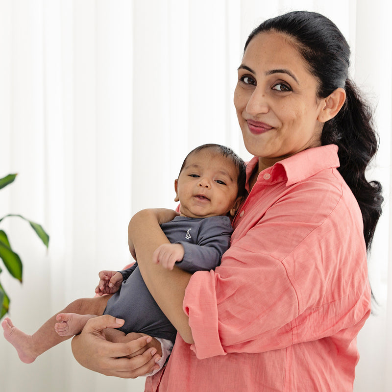 A joyful mother holding baby in an elegant Bamboo Long Sleeve Baby Onesie.