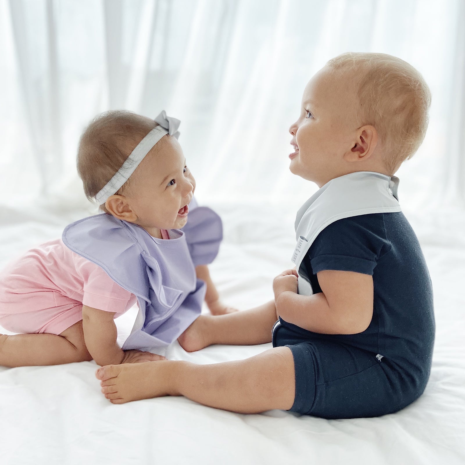 RAPH&REMY® Premium Waterproof Bib with spill-proof surface in neutral tones used by two babies