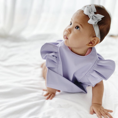 Lightweight, waterproof feeding bib from RAPH&REMY® on baby in purple color 