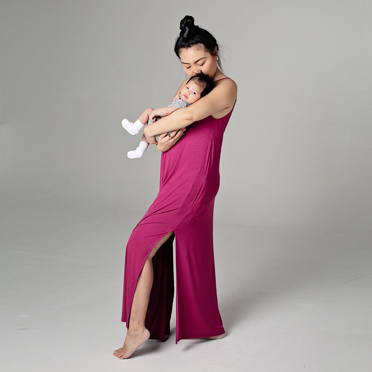 Woman holding baby in Ari dress in sangria color - left side view
