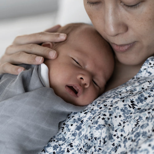 A mother holding a baby wearing grey bamboo swaddle by RAPH&REMY®