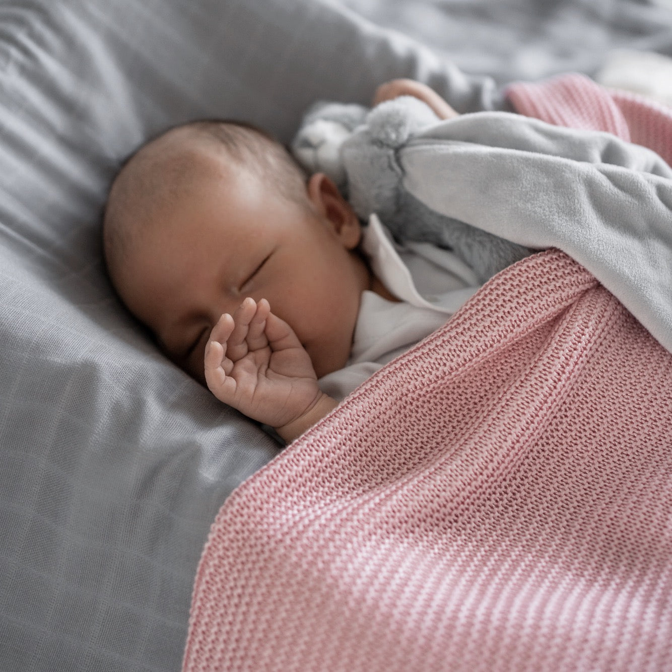 Cute baby nestled in an Organic BambooCloud Cooling Blanket by RAPH&REMY in pink color. 