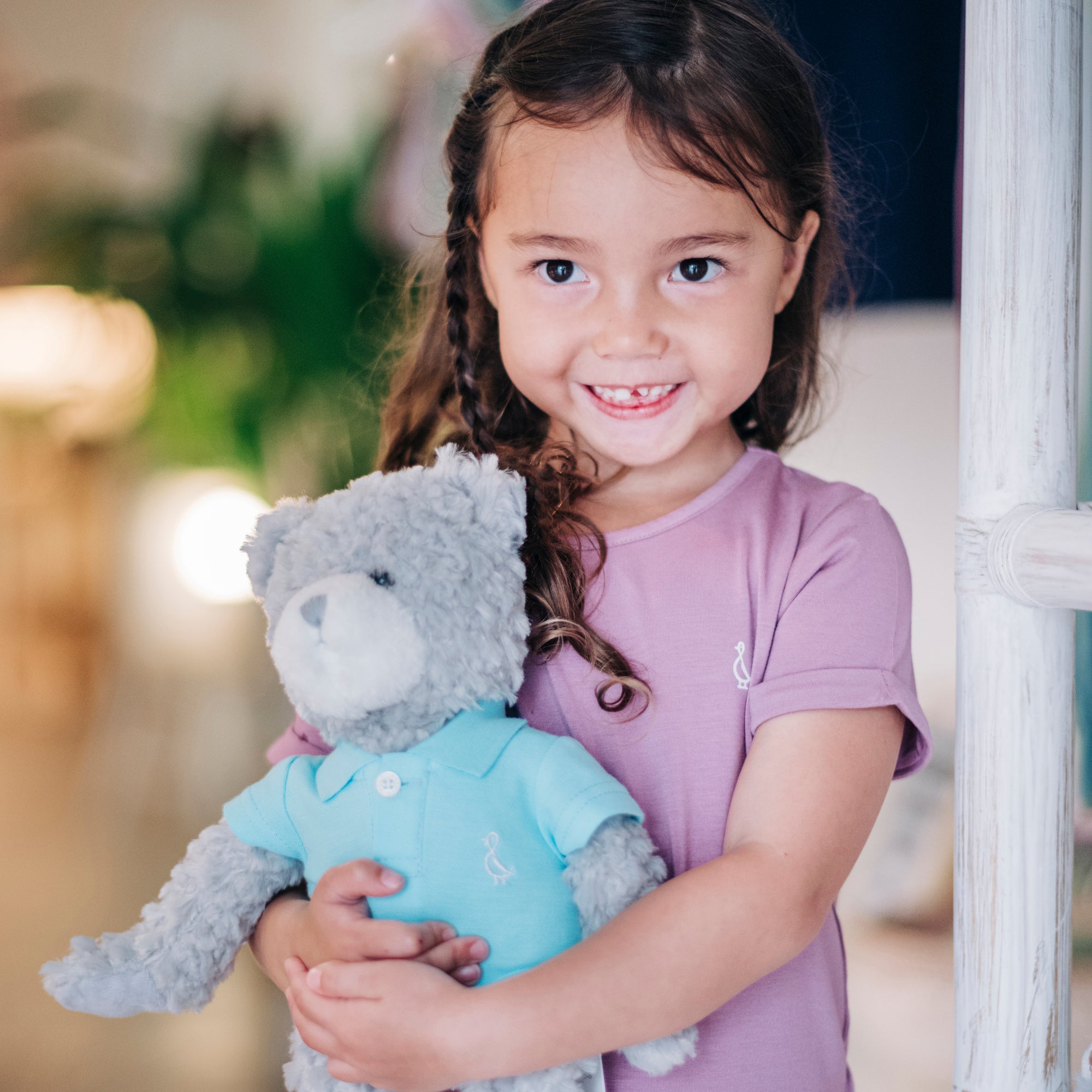 A girl holding a teddy bear while wearing a Premium Bamboo Kids T-Shirt by RAPH&REMY® in Mauve.