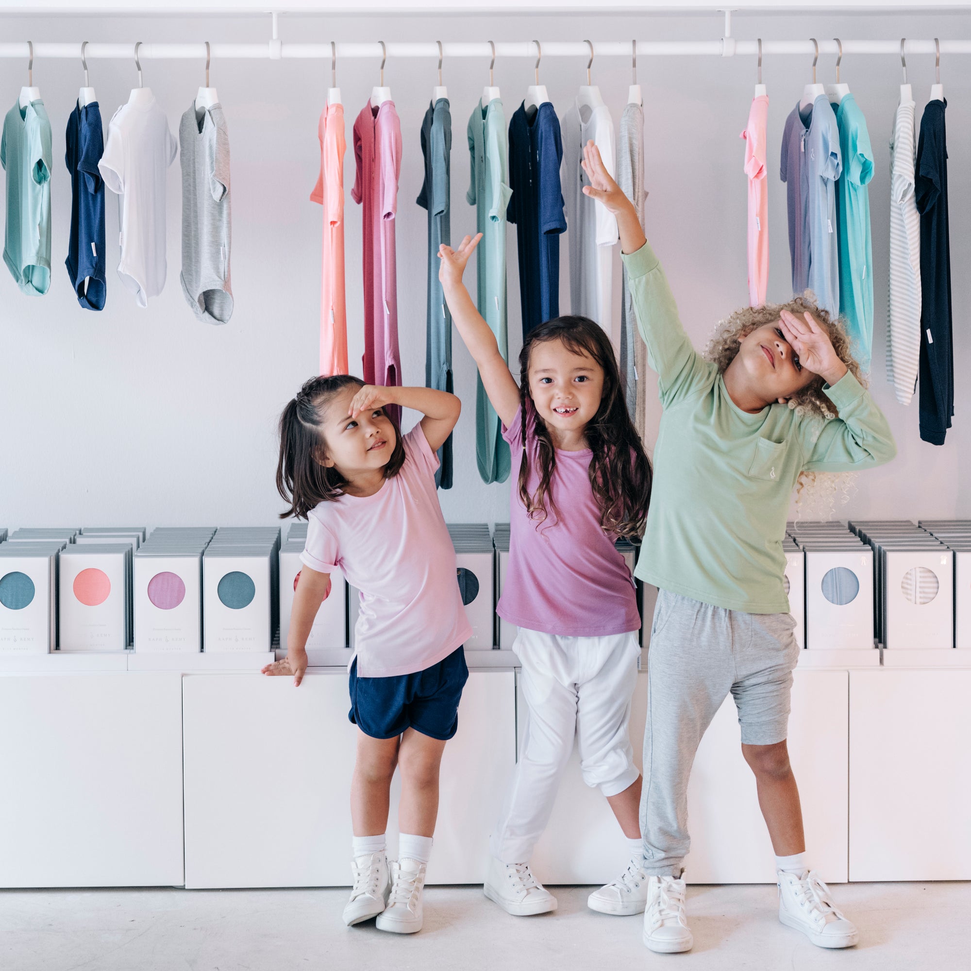 Three smiling kids wearing RAPH&REMY® Premium Bamboo T-Shirts in soft pastel shades.