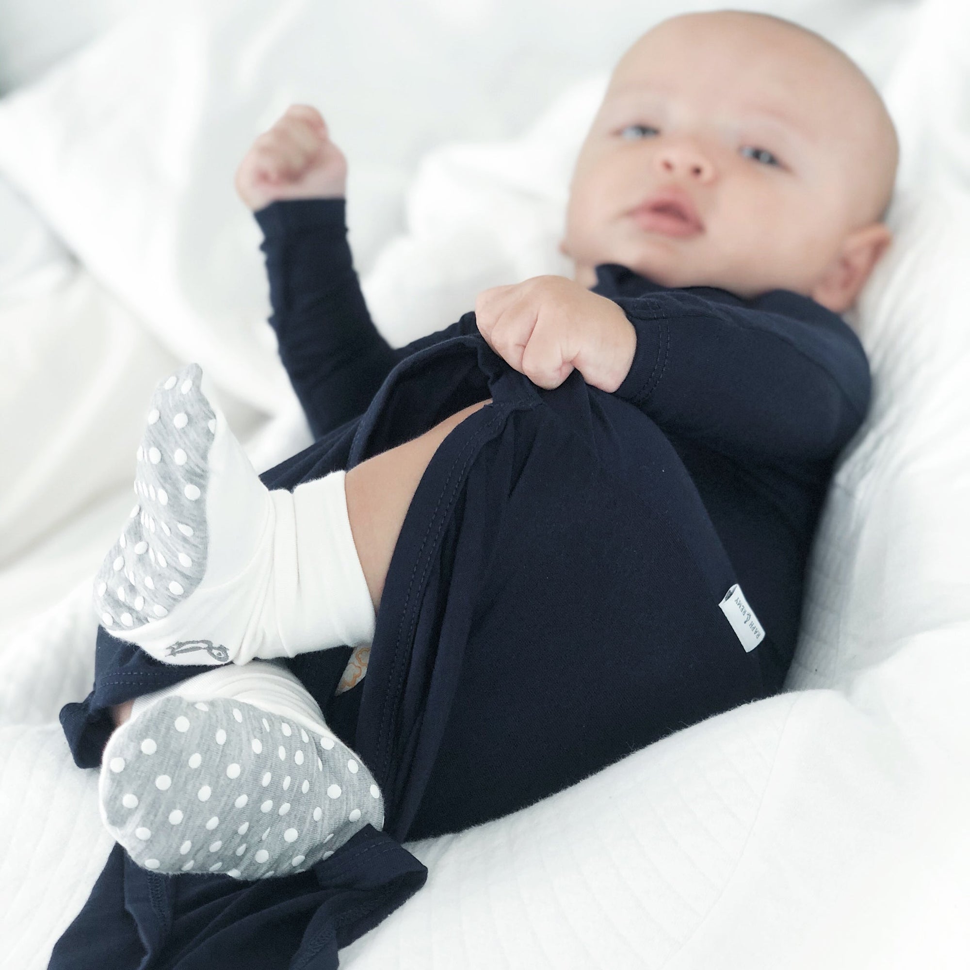 Baby lying on blanket wearing RAPH&REMY® sleep sack