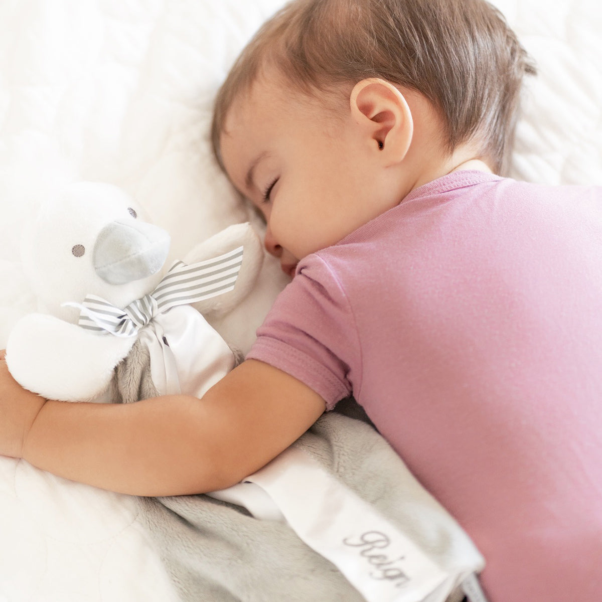 Sleeping baby holding RAPH&REMY® SootherBuddy™ Security Blanket